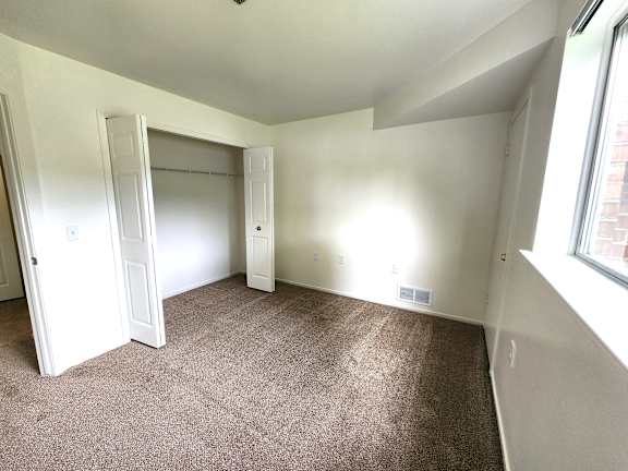A bedroom with a brown carpet and white walls.