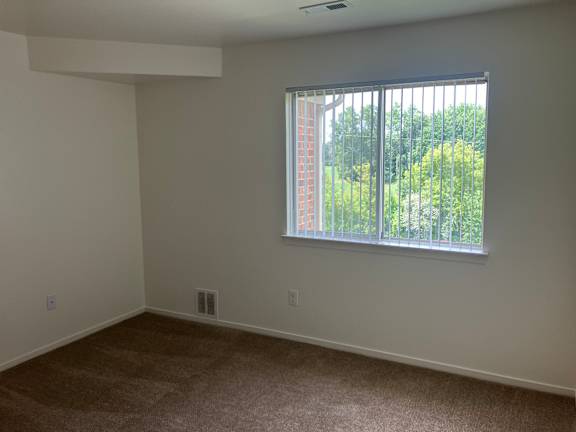 A bedroom with a window and a view of trees outside.