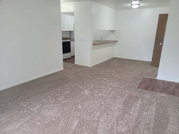 A dining room with a carpeted floor and a door on the right side.