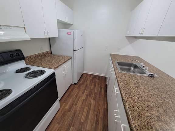 A kitchen with a white stove top oven and a white refrigerator.