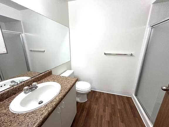 A bathroom with a brown granite countertop and a white toilet.