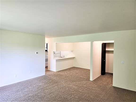 A dining room with a white wall and a brown carpet.