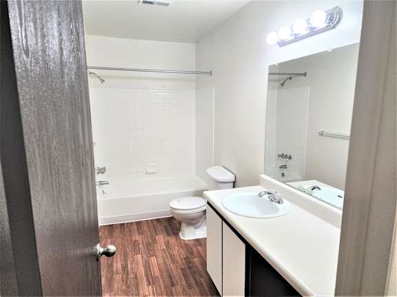 A bathroom with a toilet, sink, and mirror.
