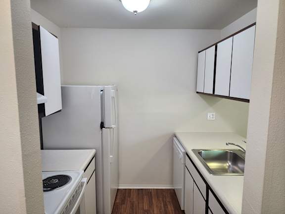 A kitchen with white appliances and cabinets.
