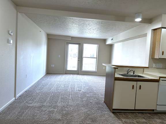 Open living room with patio door and kitchenette at Heatherwood Apartments, Grand Blanc