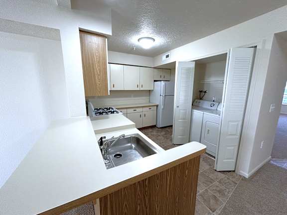 Kitchen with peninsula bar and stacked washer dryer closet at Heatherwood Apartments, Michigan