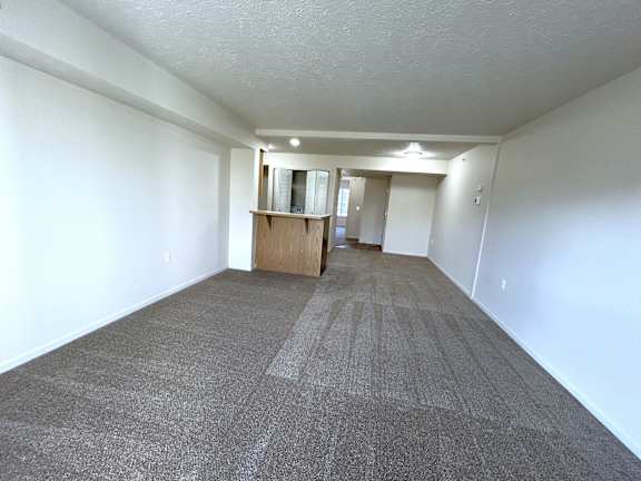 Living room with breakfast bar and entryway view at Heatherwood Apartments, Grand Blanc, MI