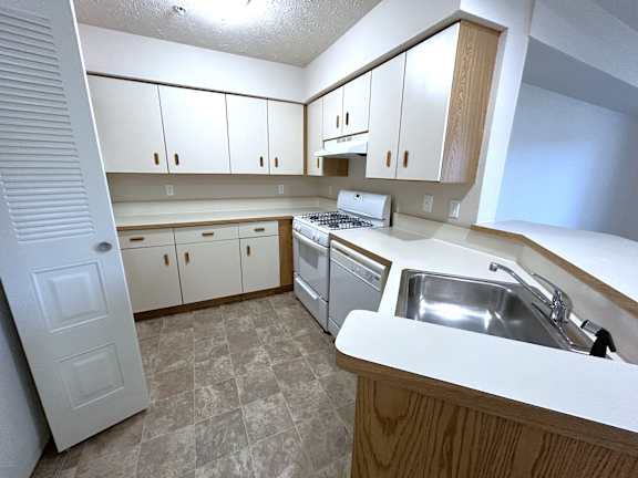 L shaped kitchen with gas range and peninsula sink at Heatherwood Apartments, Grand Blanc, 48439