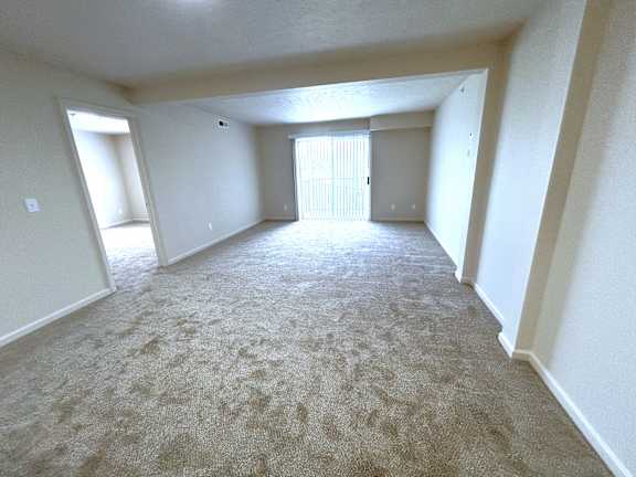 Spacious carpeted living area with patio door at Heatherwood Apartments, Michigan, 48439