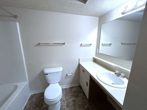 Bathroom with toilet and mirrored vanity sink at Heatherwood Apartments, Grand Blanc, Michigan