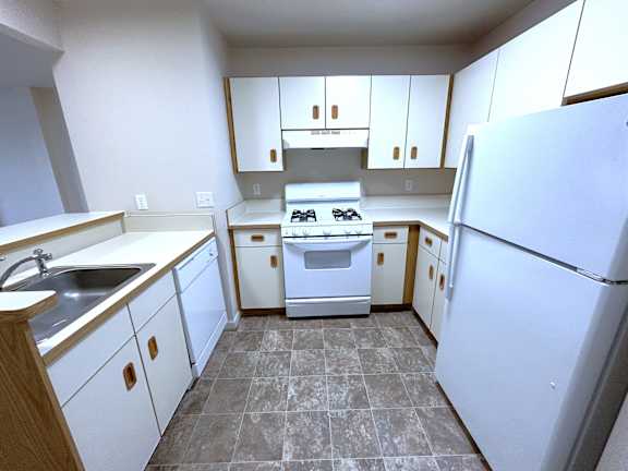Ushaped kitchen with white appliances and brown trim at Heatherwood Apartments, Grand Blanc