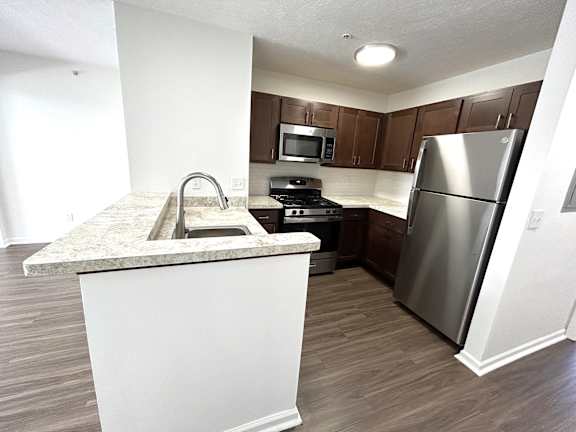 Kitchen with dark wood cabinets and stainless appliances at Heatherwood Apartments, Michigan, 48439