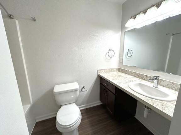 Bathroom with single sink vanity and dark wood cabinets at Heatherwood Apartments, Grand Blanc, MI 48439