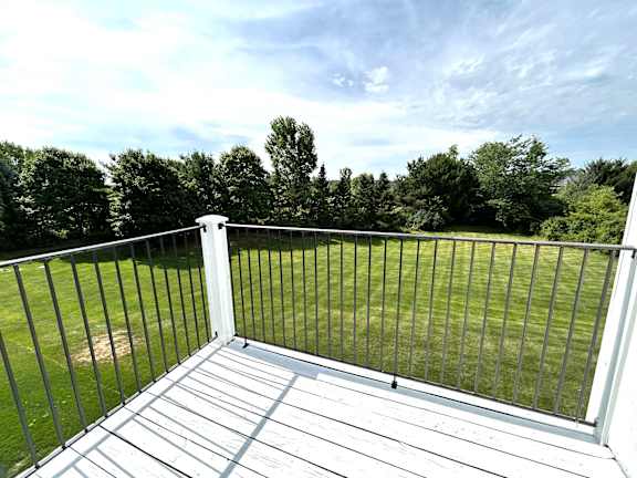 Private deck with railing overlooking green lawn and trees at Heatherwood Apartments, Grand Blanc, Michigan
