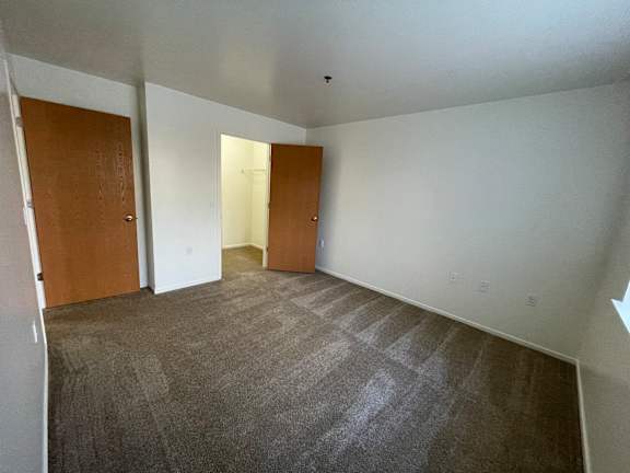A bedroom with carpeted floor and two doors.