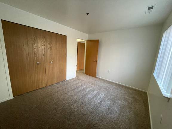 A bedroom with two brown doors and a carpeted floor.
