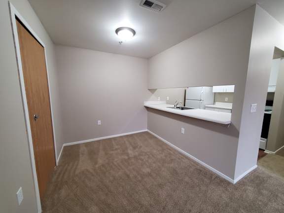 A dining room with a carpeted floor and a wooden door.