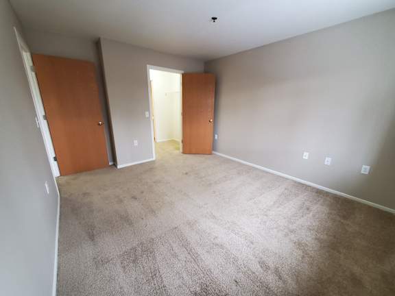 A bedroom with carpeted floor and two doors.