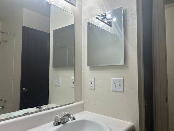 A white sink in a bathroom with a mirror above it.