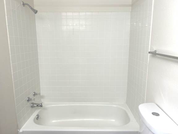 A white bathroom with a white tub and toilet.
