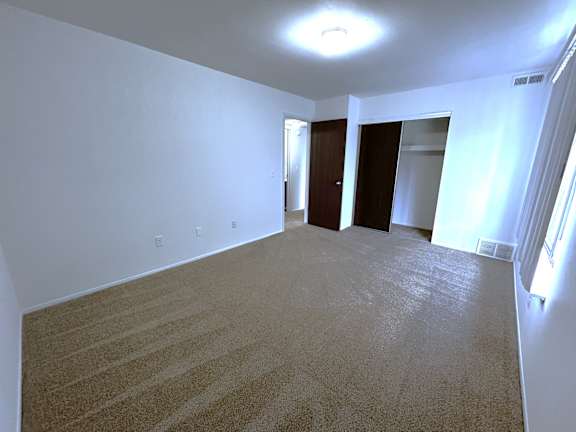 A bedroom with a carpeted floor and a ceiling light.