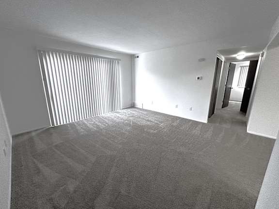 A living room with a carpeted floor and a sliding door.