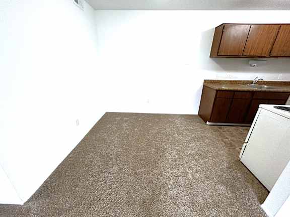 Kitchen with wood cabinets and beige carpeted flooring at Charter Oaks Apartments, Davison, Michigan