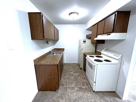A kitchen with white stove and brown cabinetry 1 at Charter Oaks Apartments, Davison, 48423