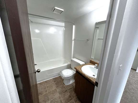 A bathroom with tub shower combo and granite vanity at Charter Oaks Apartments, Davison, MI, 48423