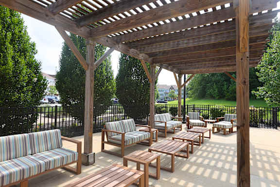 A wooden pergola with striped couches and tables.