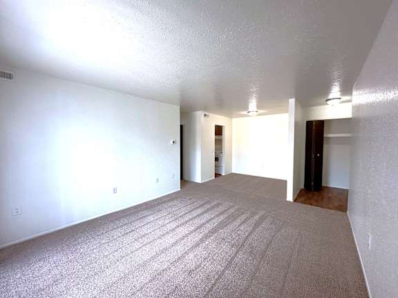 A living room with a carpeted floor and white walls.l