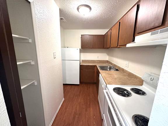 A kitchen with a white fridge and stove top oven.