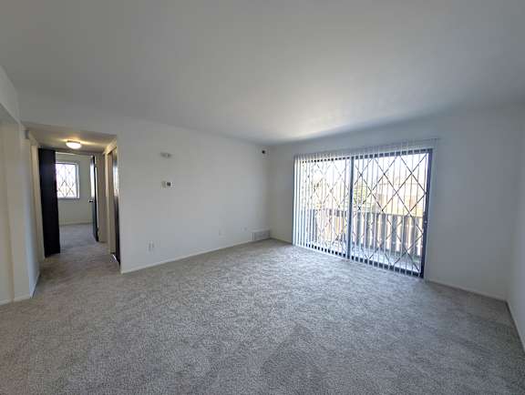 Bright living room with vertical blinds and hallway at Charter Oaks Apartments, Davison, Michigan