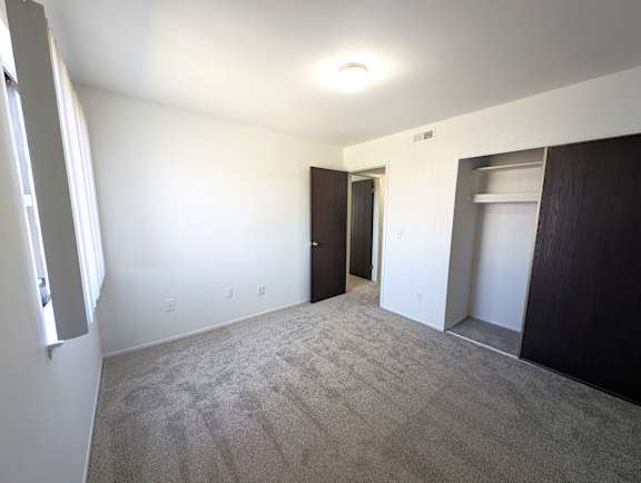 Empty bedroom with walk-in closet and carpet at Charter Oaks Apartments, Davison