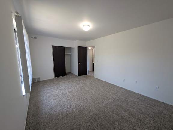 Spacious bedroom with double closets and neutral carpet at Charter Oaks Apartments, Michigan, 48423