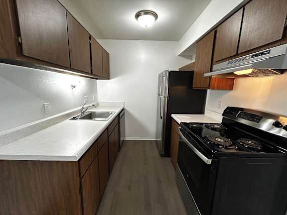 Galley kitchen with electric range and overhead lighting at Charter Oaks Apartments, Michigan