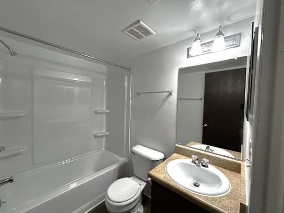 Bathroom with white fixtures and mirrored vanity at Charter Oaks Apartments, Davison, Michigan