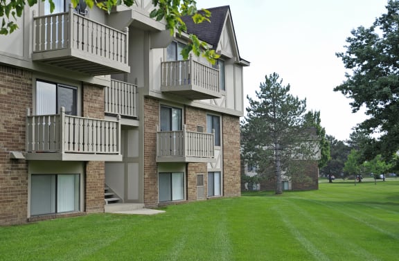 an apartment building with balconies and a green lawn at Rivers Edge Apartments, Waterford Twp, 48327