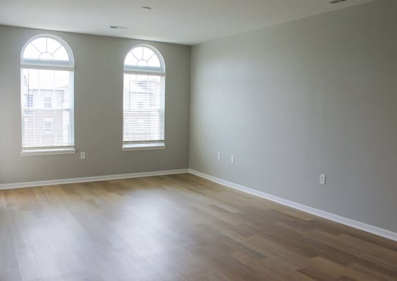 an empty room with hardwood floors and two windows  at Alexandria of Carmel Apartments, Carmel, IN, 46032