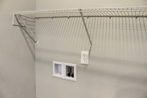 a wire closet organizer hangs on the wall next to two outlets  at Alexandria of Carmel Apartments, Carmel