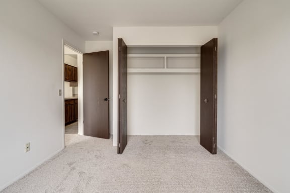 a walk in closet in a bedroom with white walls and carpet at The Landings Apartments, Westland, 48185