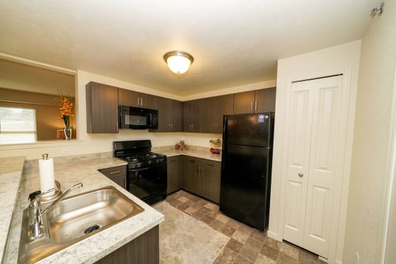 a kitchen with a sink and a black refrigerator  at Andover Pointe Apartment Homes, La Vista