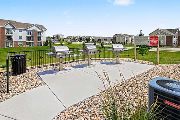 A row of stainless steel BBQ grills on a concrete slab at Andover Pointe Apartment Homes in La Vista, NE
