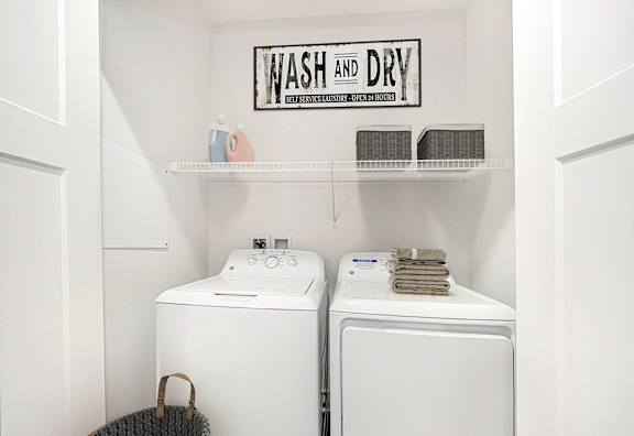 A laundry area with a washer and dryer and a shelf above them at Andover Pointe Apartment Homes, La Vista, NE, 68138