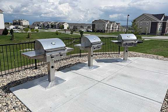 A row of stainless steel BBQ grills on a concrete slab at Andover Pointe Apartment Homes in La Vista, NE