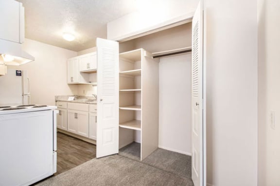 a kitchen with white cabinets and a large closet with shelving