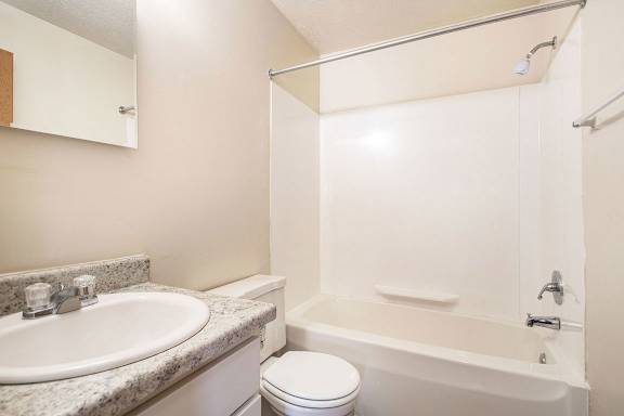 A white bathroom with a toilet, sink, and bathtub at Apple Ridge Apartments, Michigan, 49534