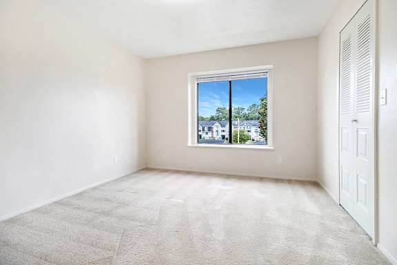 A bedroom with a carpeted floor and a window at Arbor Lakes Apartments in Elkhart, IN