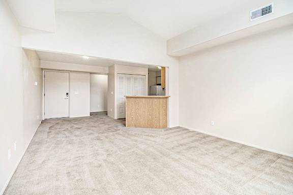A living room with a carpeted floor and a breakfast bar at Arbor Lakes Apartments in Elkhart, IN