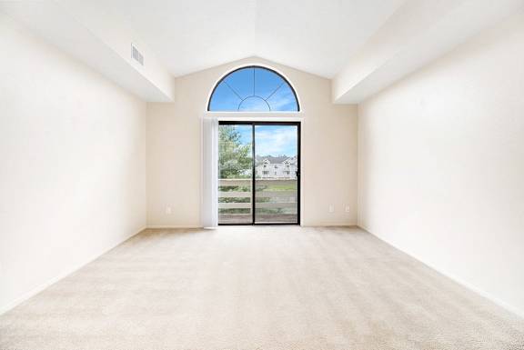 A living room with a large window and a cathedral ceiling at Arbor Lakes Apartments in Elkhart, IN